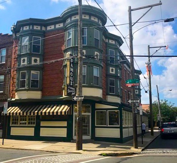 A corner brick building with a vertical sign that reads Famous