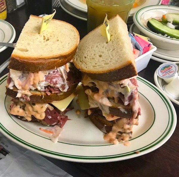 A huge overstuffed hot pastrami sandwich on rye with coleslaw and Russian Dressing