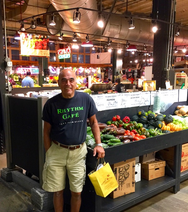 A man standing with a shopping bag at a farmers market