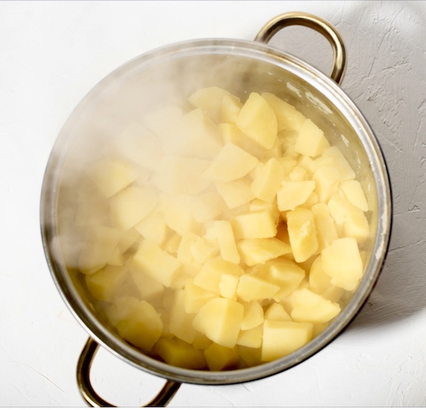 Cut potatoes in a pot of steaming water cooking for my Garlic Horseradish Mashed Potatoes recipe