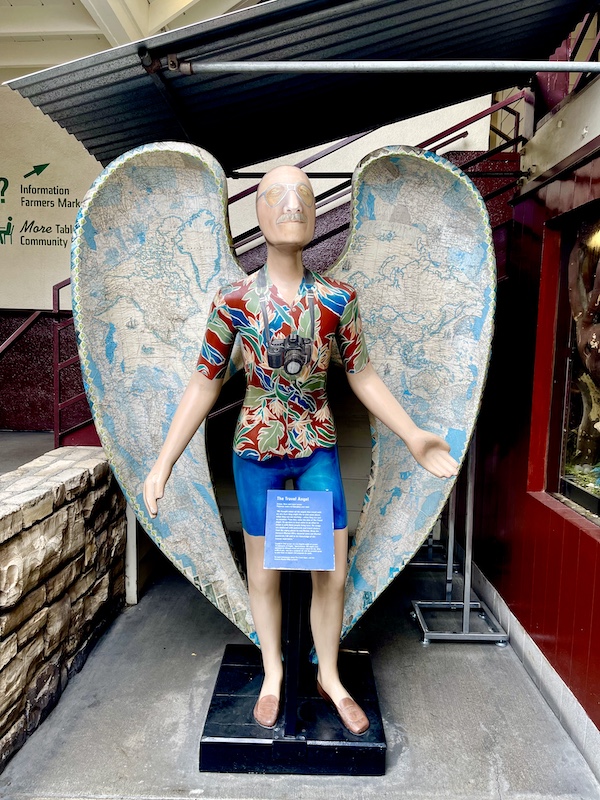 Sculpture of a man with wings wearing a tropical shirt and shorts at the Original Farmers Market L.A.