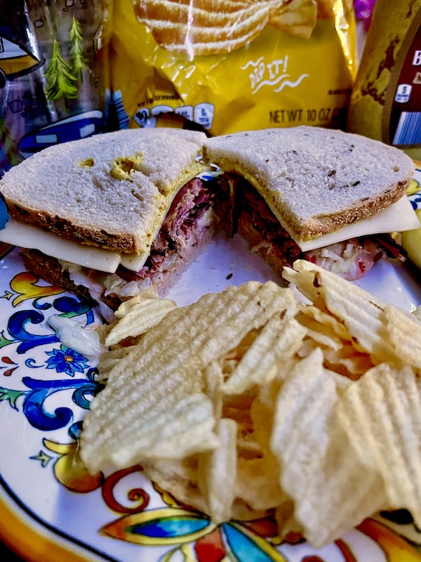 Pastrami sandwich on rye with Swiss cheese, coleslaw and Russian Dressing and potato chips from Canter's Deli on Fairfax