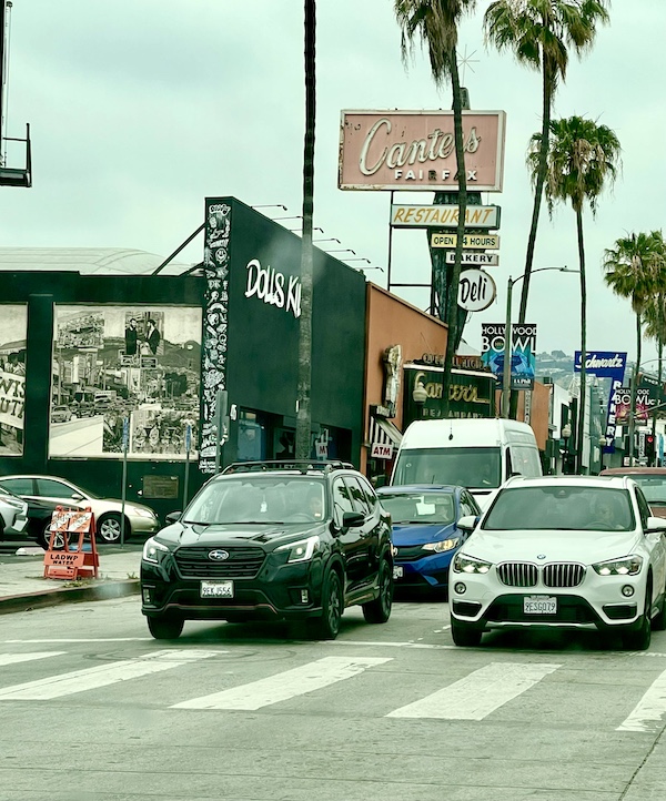 Busy street with many cars passing in front of Canter's Deli on Fairfax