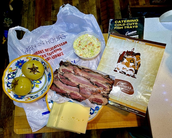 Wood counter displaying menu, pastrami, cheese and pickles from Canter's Deli on Fairfax