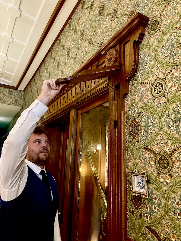 Man showing us another hidden compartment in the hotel lobby.