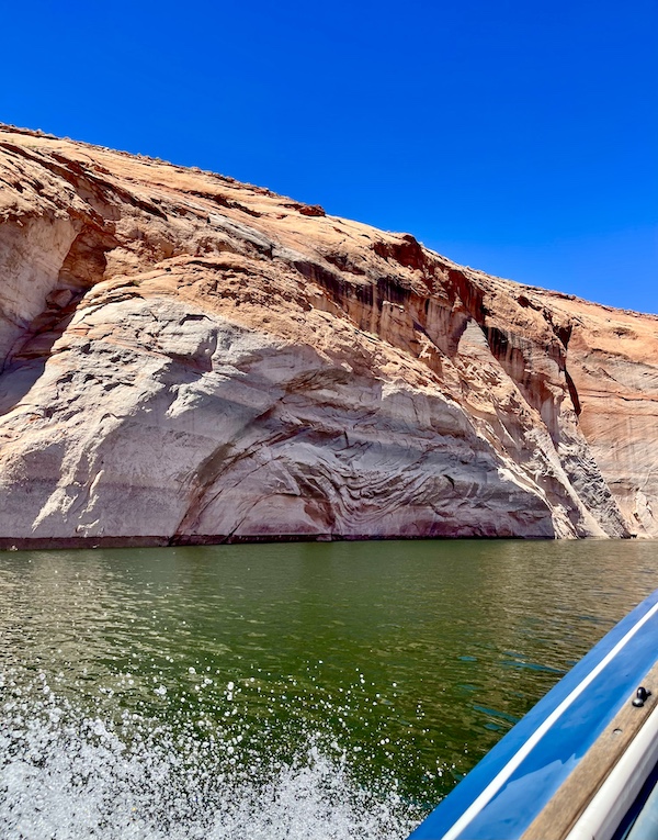 Rock formation in the lake that looks like it's been painted with rust colored swirls.