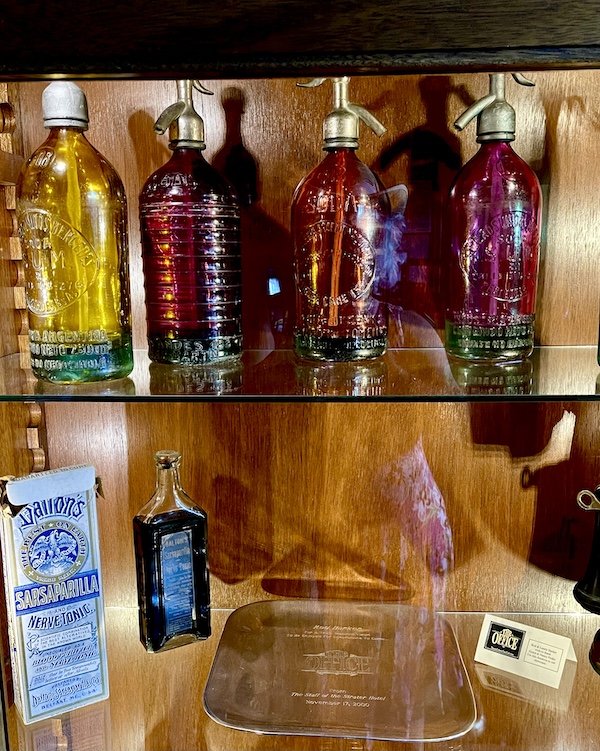 Colorful glass spritz bottles on display in a glass case.