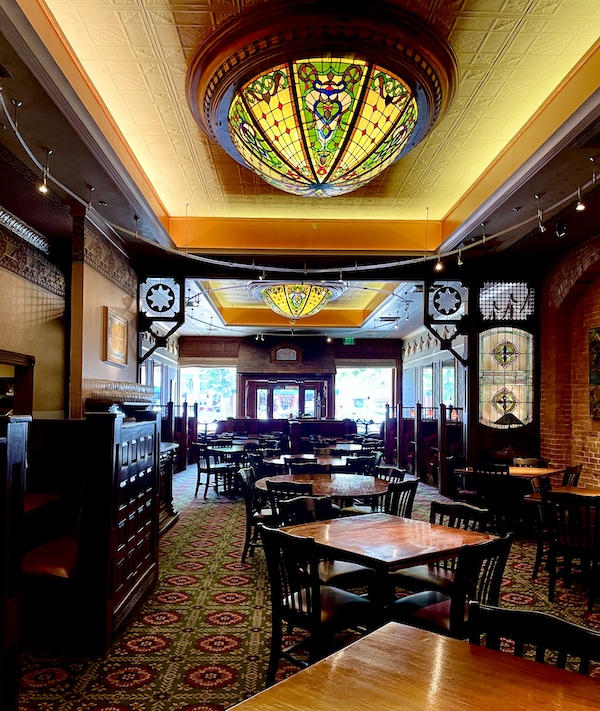 Tavern with dark wood tables and chairs and Tiffany glass ceiling lights at Strater Hotel Durango Colorado