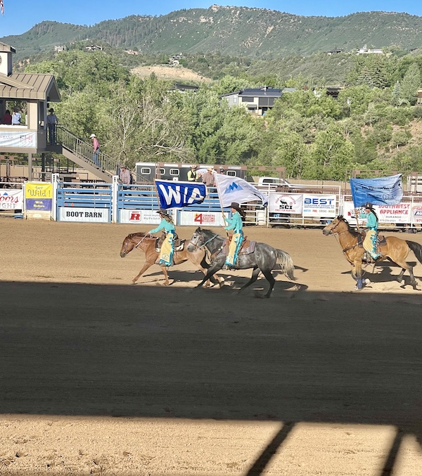 Three female riders on horseback; wearing turquoise shirts and yellow chaps at Our First Rodeo Durango CO