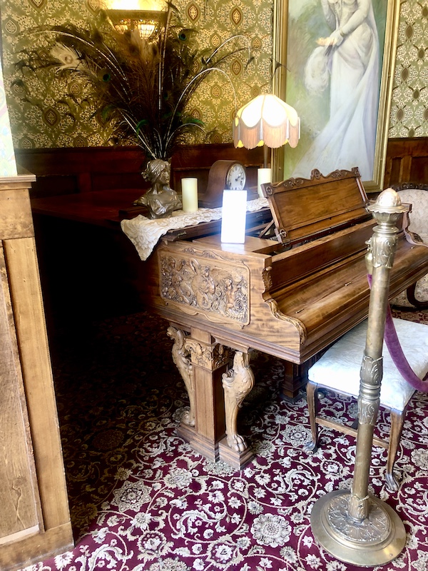 Ornately carved medium brown wood piano at hotel in Silverton CO